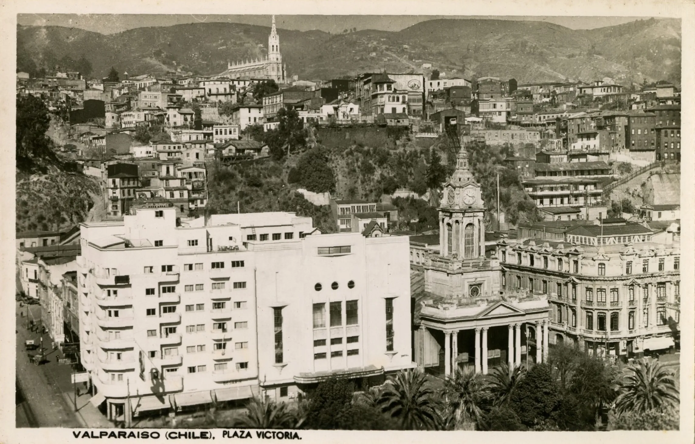 Valparaíso (Chile), Plaza Victoria : [Teatro Valparaíso, contiguo al edificio de Rentas para la Cooperativa Vitalicia; Iglesia del Espíritu Santo, y Club Naval, cerros de Valparaiso] [fotografía]. Archivo Fotográfico. . Disponible en Biblioteca Nacional Digital de Chile https://www.bibliotecanacionaldigital.gob.cl/bnd/629/w3-article-612713.html . Accedido en 12/8/2025.